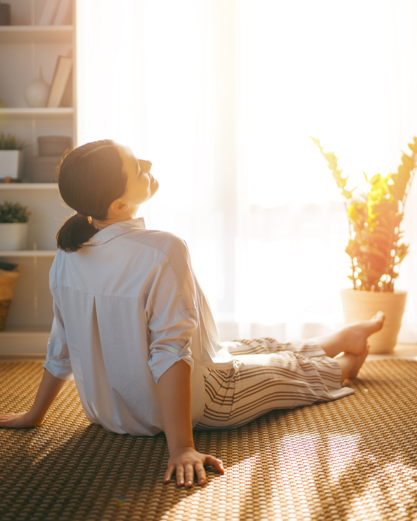 Frau atmet am Boden im Morgenlicht - Helfer im Alltag schenken die Pause